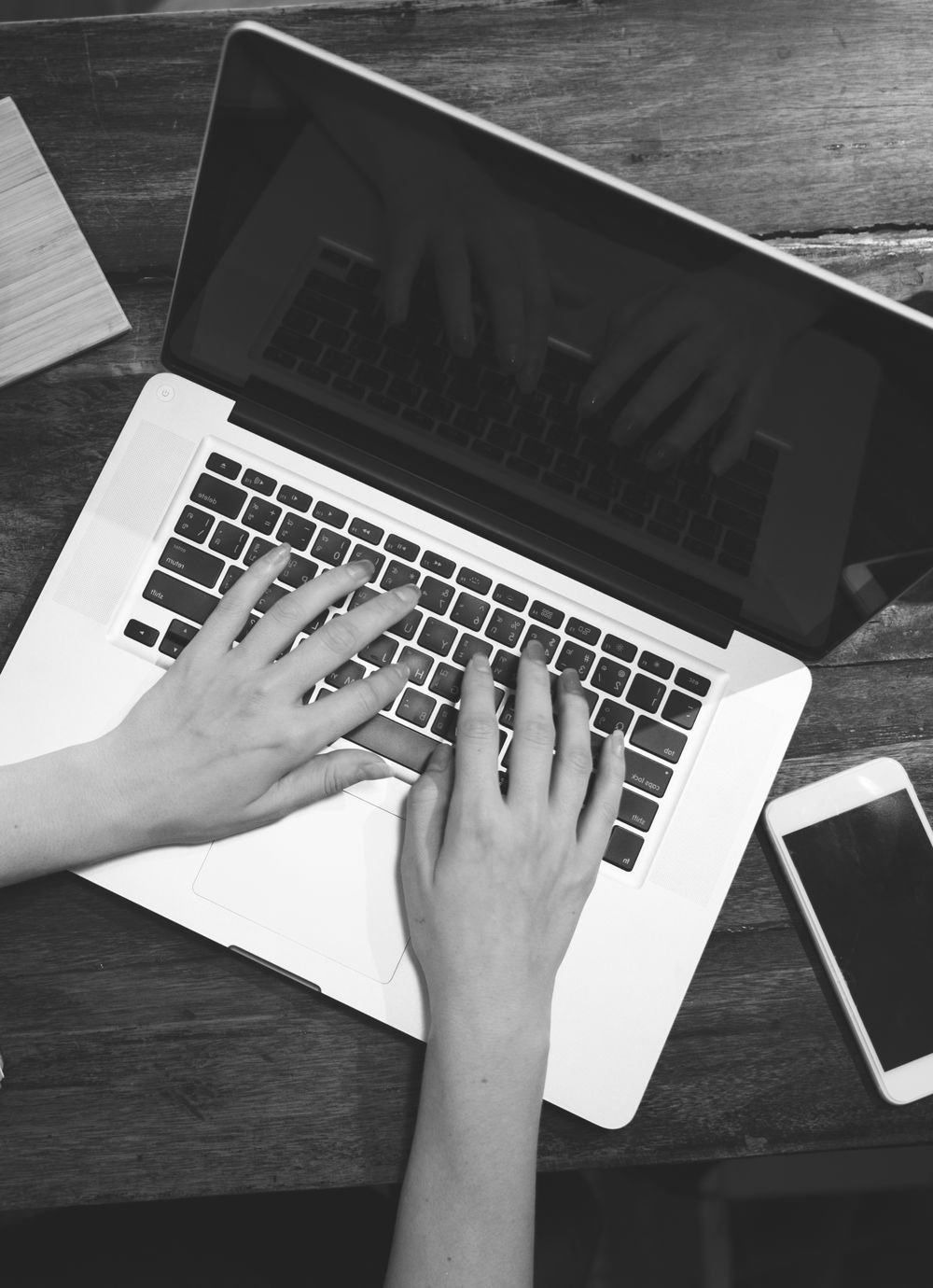 Hands typing on a laptop at a desk with coffee and notes
